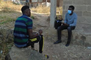 Male research assistant interviewing a young man using a tablet